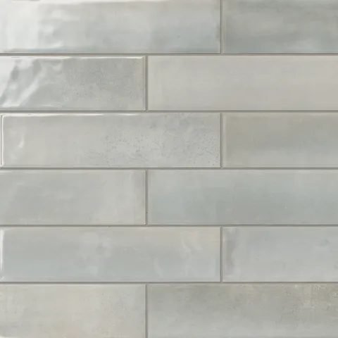 Light grey glossy subway tiles with subtle tonal variations, offering a sleek and versatile option for modern interior designs.