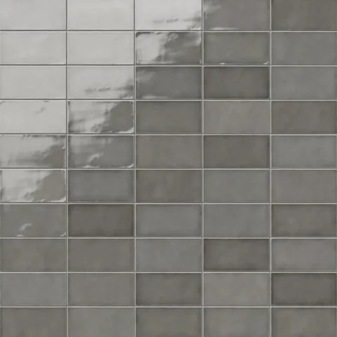 Mikayla ceramic subway tiles in a deep, muted gray tone, showcasing a smooth glossy finish with subtle light reflections for a sophisticated handmade look