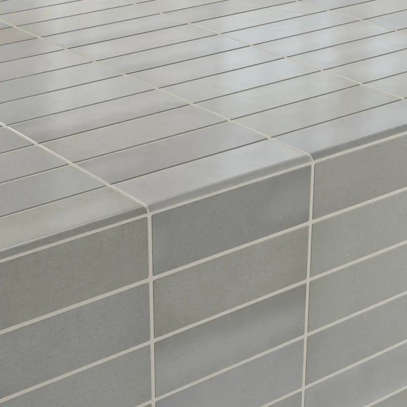 Pebble-gray bullnose tile installation showcasing a soft matte finish with smooth, modern edges
