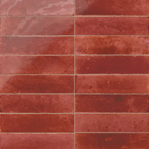 Glossy subway porcelain tiles in a rich brick red shade, featuring tonal shifts and a handcrafted look.
