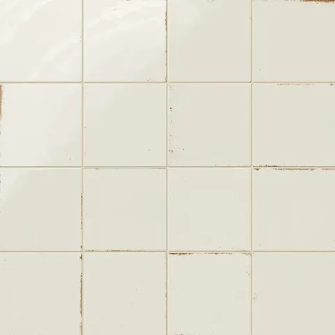 Soft white porcelain tiles featuring a glazed finish with worn accents that create a vintage, timeworn effect.