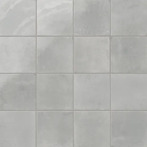 Glossy porcelain wall tiles in mixed gray tones, featuring a softly textured, rustic finish.