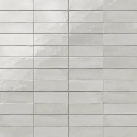 Glossy subway tiles in shifting light gray tones with an artisan-like surface and subtle reflective finish