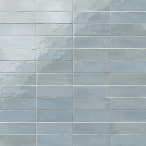 Glossy subway tiles in soft pastel blue tones with subtle shade variations and an artisan-like finish.