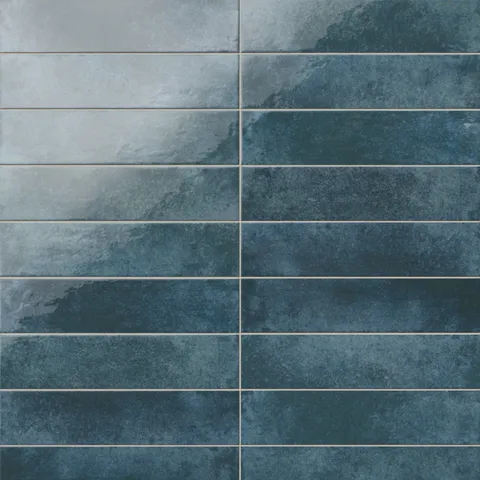 Marine blue glossy porcelain tile with shifting deep and weathered tones, its artisan-like surface and elongated form creating fluid movement, ideal for coastal and Mediterranean interiors.