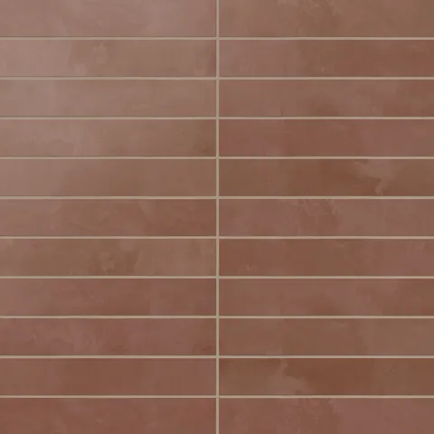 A run of 2.5x12 matte porcelain subway tiles reveals rich red shading with subtle surface variation, where earth-drawn tones and a powdery glaze soften the look.