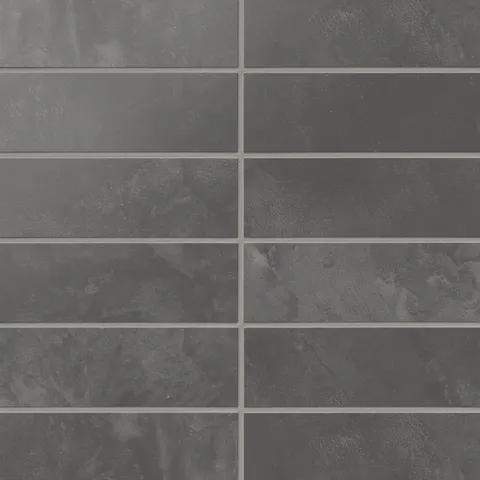 Dark gray 2x6 matte subway tiles show shifting, earth-drawn tones across the surface, laying out in a calm horizontal rhythm that suits kitchens and baths.