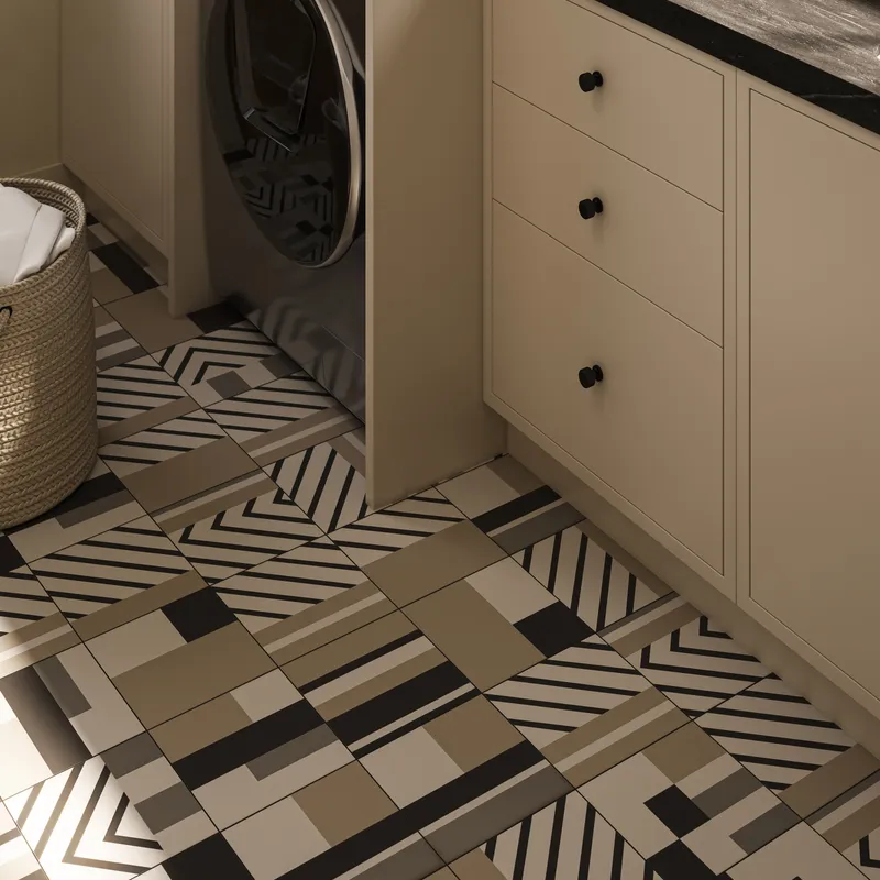 Modern laundry room with bold geometric floor tiles in black, taupe, and cream, paired with beige cabinetry and dark stone countertop.