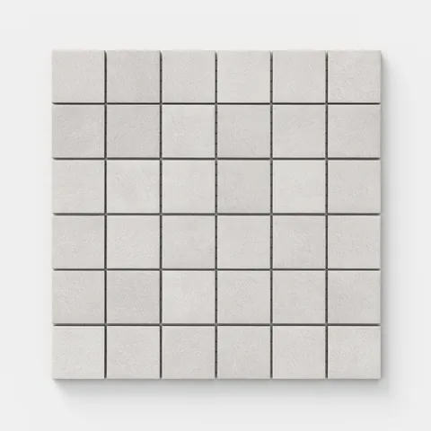 Square mosaic tiles with a subtly textured surface and gentle shifts of light gray tones, echoing hand-formed clay.