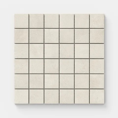 Square mosaic tiles with a subtly textured surface and gentle shifts of grayish beige tones, echoing the traces of hand-formed clay.