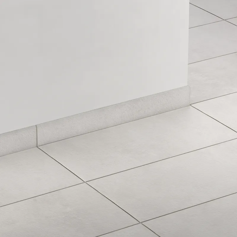 Elongated subway-style trim in soft light gray with a curved front edge, creating a clean, smooth transition between wall and floor.