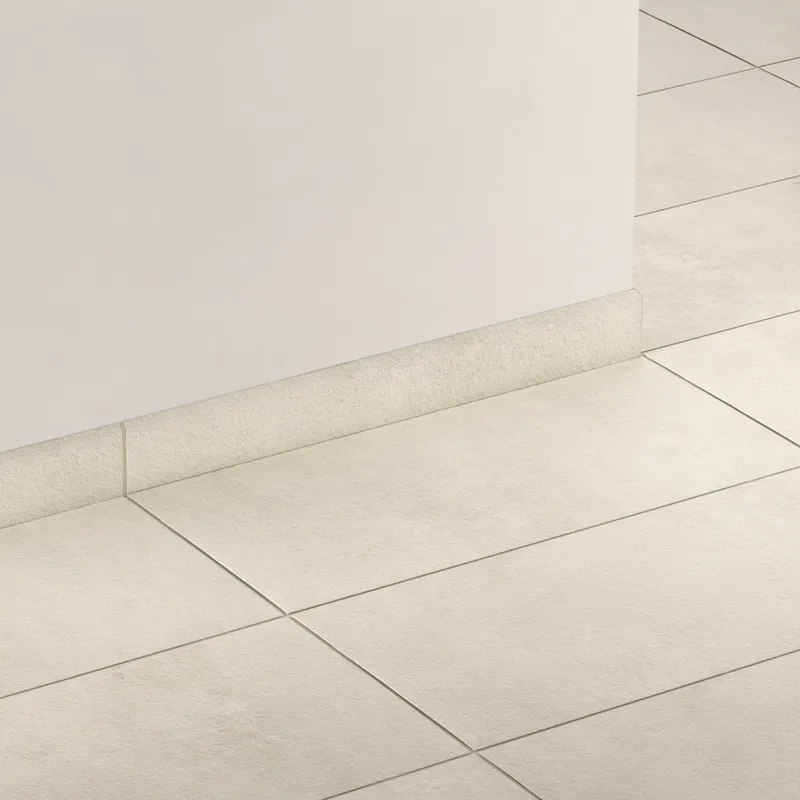 Elongated subway-style trim with a curved front edge in soft grayish beige, creating a smooth transition between wall and floor.
