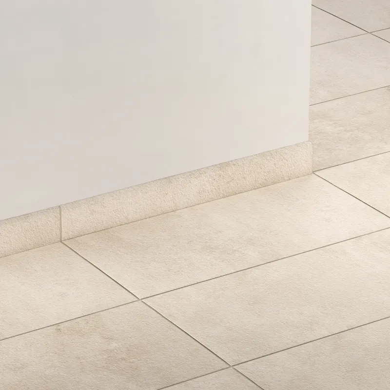 Elongated subway-style trim with a curved front edge in warm beige, creating a clean, smooth transition between wall and floor.