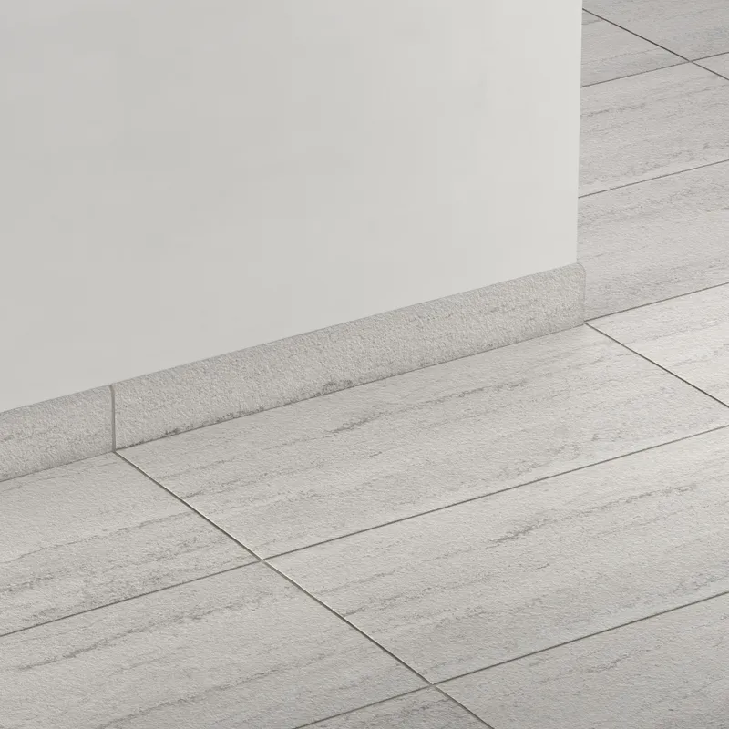 Elongated subway-style trim in light gray with a subtly textured surface, creating a smooth transition between wall and floor.