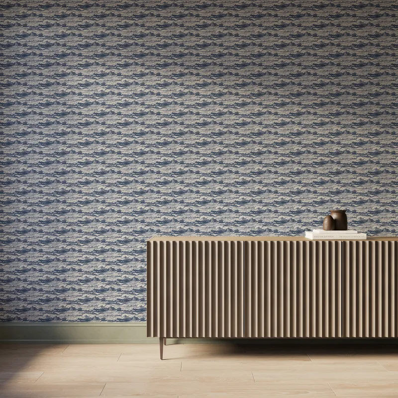 Blue and cream wave-pattern wallpaper installed on a wall behind a modern ribbed wood sideboard with books and pottery decor.