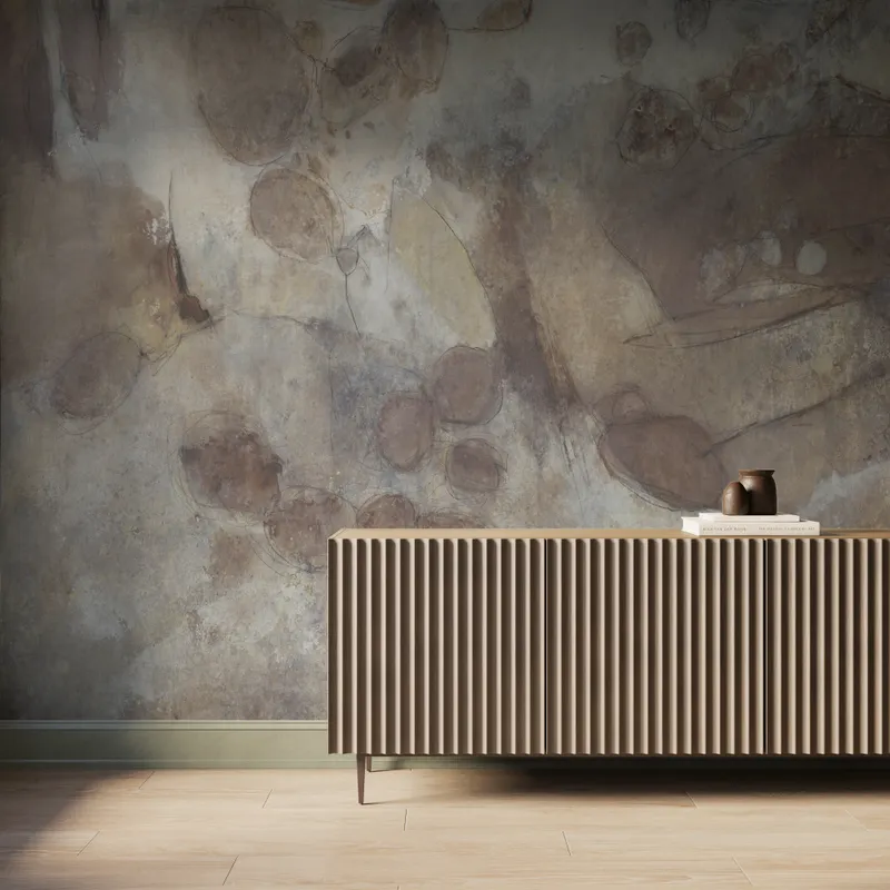 Interior scene featuring the Skyveil Mural in Mistfall II with layered light beige and rusty brown abstract textures, styled behind a fluted wood console cabinet with light wood flooring and soft natural light washing across the wall.