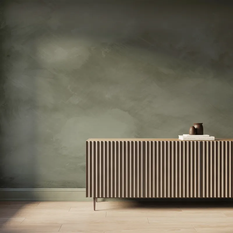 Gallery-scale olive green abstract limewash-look wallpaper mural with soft tonal texture, styled behind a modern fluted wood console.