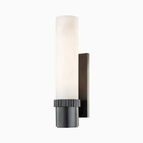 Asha wall sconce in old bronze with a grooved cylindrical base and alabaster shade, fusing moody sophistication with soft illumination