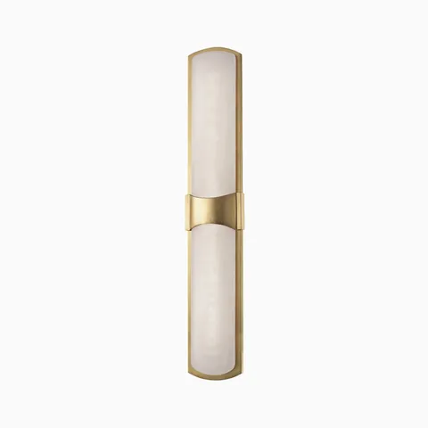 Slim vertical wall sconce with a frosted glass shade and aged brass frame, featuring a curved center bracket for mounting.