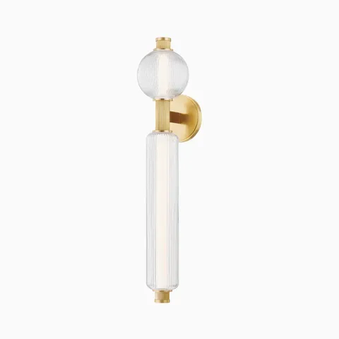 Vertical wall sconce with ribbed glass globe and cylindrical shade, mounted on a round vintage brass base with decorative end caps.