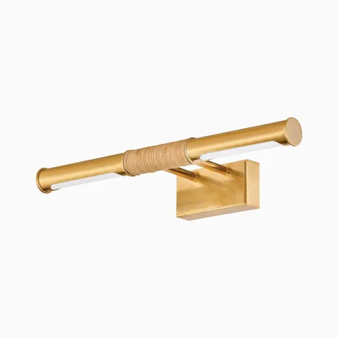 Picture light in aged brass with a rattan-wrapped center and curved frame, blending classic form with natural, organic texture.