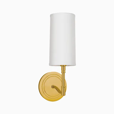 Aged brass wall sconce with round backplate, curved arm, and tall white fabric shade, offering a refined classic lighting accent.
