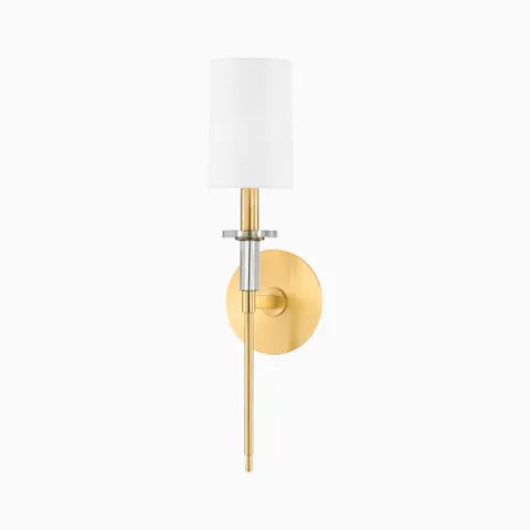Aged brass wall sconce with white cylindrical shade, slim vertical rod, and round backplate for a refined modern lighting accent.