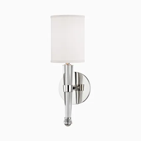 Wall sconce with polished nickel round backplate, tapered metallic stem, and white silk cylinder shade for soft, ambient lighting.