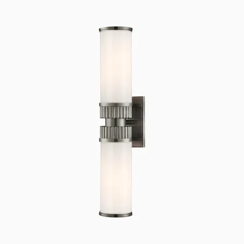 Wall sconce with twin opal glass cylinders and fluted antique nickel center band, offering Art Deco-inspired elegance with a modern edge.