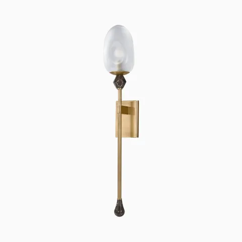 Slim and elegant, the Shonda Wall Sconce in Vintage Brass showcases a gemstone-inspired silhouette, golden frame, and clear etched glass top.