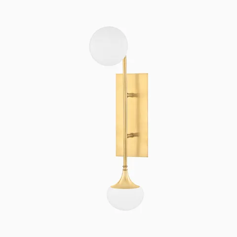 Wall sconce in aged brass with two white glass globes on a slim brass stem, mounted vertically on a rectangular brass backplate.