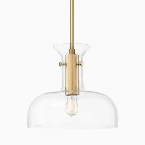 Pendant light in aged brass with a cylindrical metal fixture and clear glass shade, showcasing an exposed vintage-style bulb.