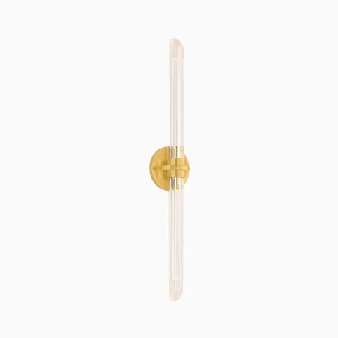 Slim vertical wall sconce with ribbed glass rods and a round gold base, designed for refined ambient lighting in modern interiors.