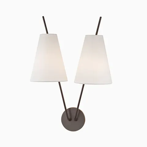 Old bronze wall sconce with round backplate, dual angled arms, and tapered white fabric shades for a sleek modern symmetrical design.