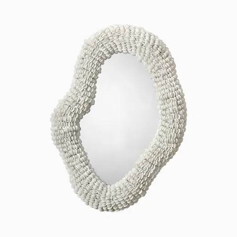 Organic oval wall mirror with a sculptural white shell-beaded frame, adding layered texture and coastal elegance to modern interiors.
