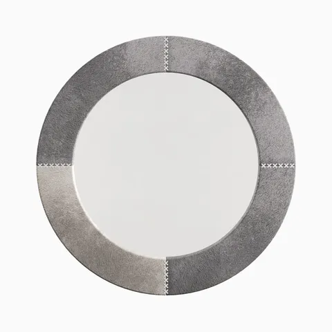 Round mirror wrapped in gray hair-on cowhide with subtle tonal variation and white leather whip-stitch accents referencing classic saddlework.