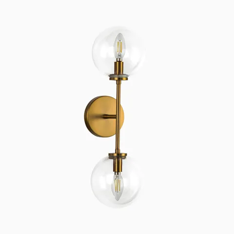 Modern wall sconce with dual clear glass globe shades and brushed brass vertical metal arm.