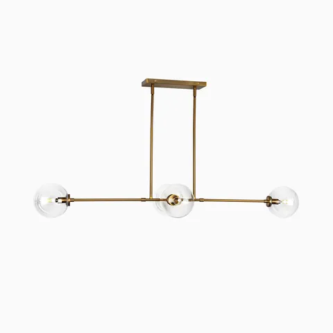 Modern linear pendant light with three clear glass globe shades on a brushed brass horizontal frame.