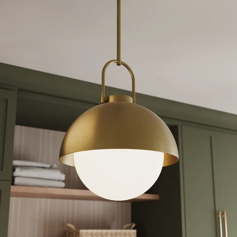 Aged gold dome pendant light with a matte opal glass globe hanging in a kitchen interior.