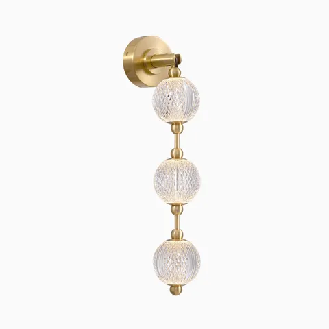 Brushed gold LED wall light with three vertically arranged textured glass globe shades, offering layered sparkle and warm ambient lighting for bathroom vanity areas.