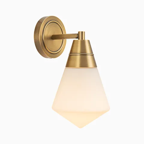 Wall vanity light in brushed gold with a geometric frosted glass shade and tapered metal top extending from a round backplate.